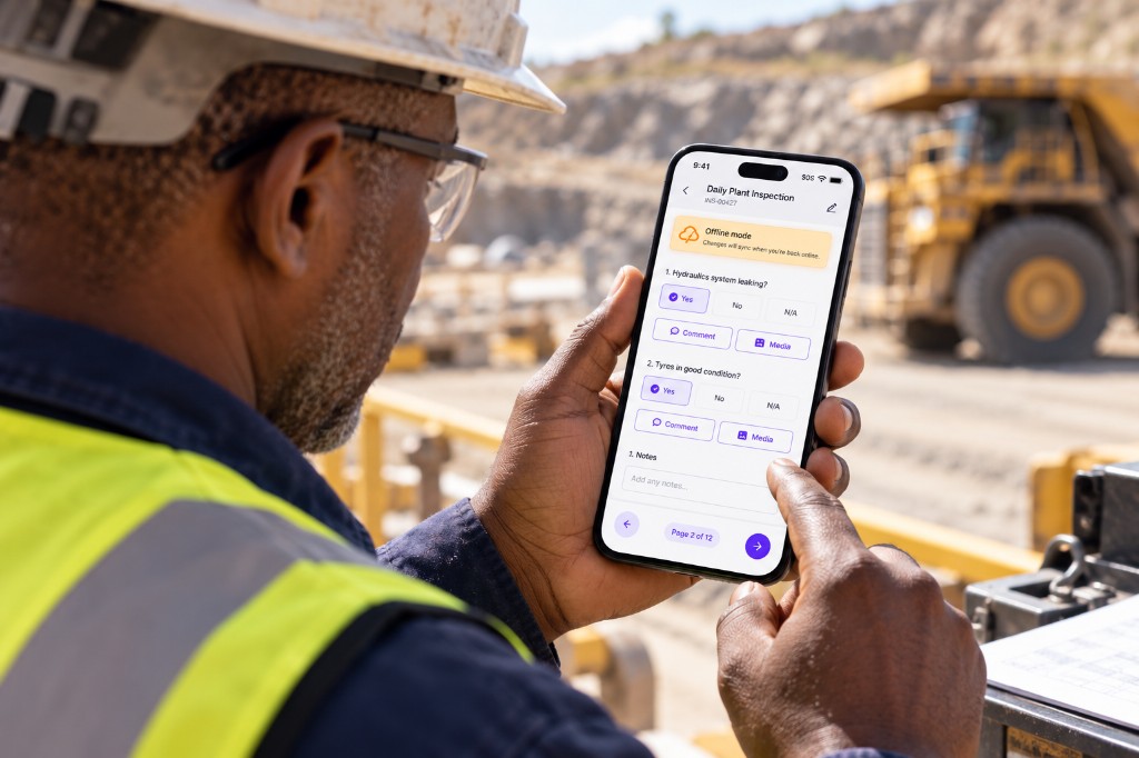 Supervisor completing a daily plant inspection on a phone in offline mode beside a haul truck